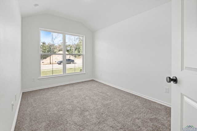 carpeted spare room featuring vaulted ceiling