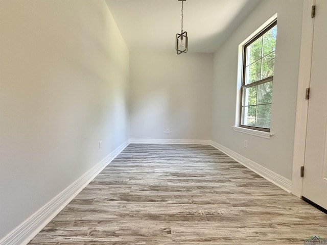 unfurnished dining area featuring wood finished floors and baseboards