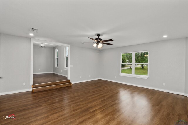 unfurnished room featuring ceiling fan with notable chandelier and dark hardwood / wood-style floors