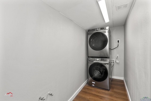 washroom featuring dark hardwood / wood-style floors and stacked washer / dryer