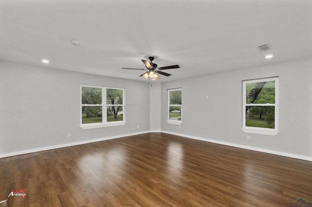 empty room with a wealth of natural light, dark wood-type flooring, and ceiling fan