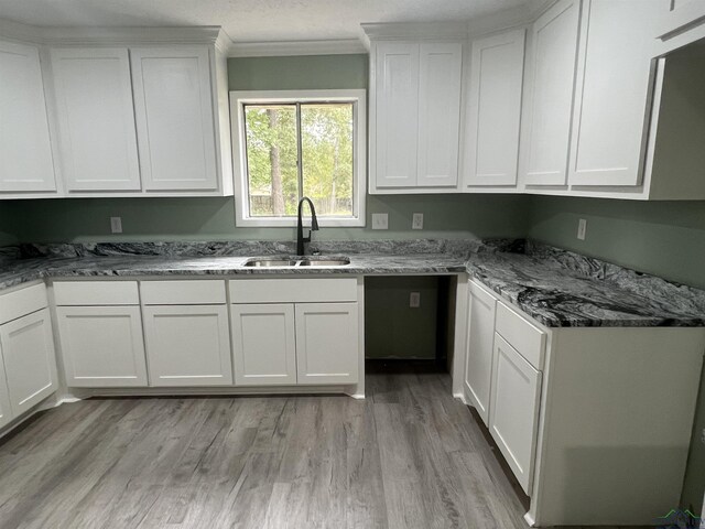 kitchen featuring white cabinets, stone countertops, light hardwood / wood-style floors, and sink