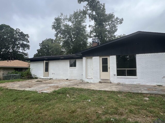 back of property featuring a lawn and a patio