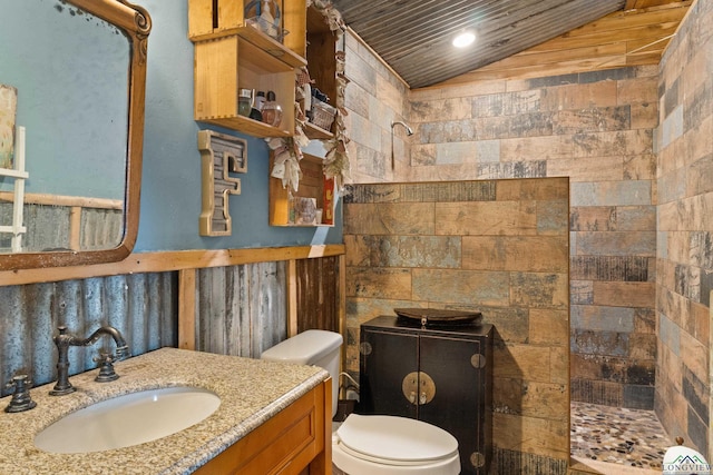 bathroom featuring a tile shower, vanity, vaulted ceiling, and toilet