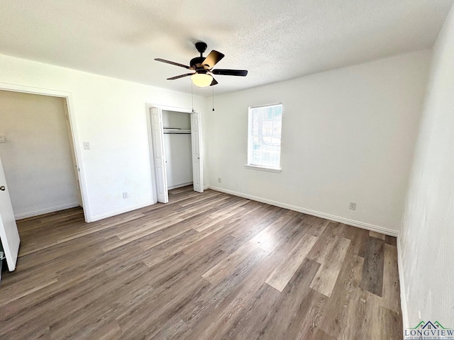 unfurnished bedroom featuring wood finished floors, baseboards, ceiling fan, a closet, and a textured ceiling