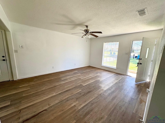 unfurnished room featuring visible vents, baseboards, ceiling fan, a textured ceiling, and dark wood-style flooring