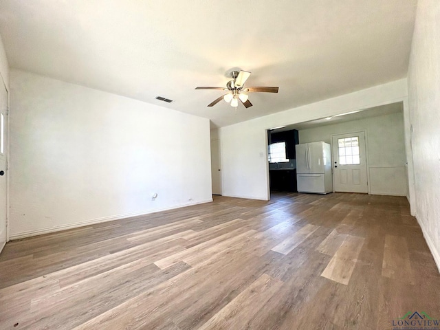 unfurnished living room featuring a ceiling fan, wood finished floors, visible vents, and baseboards