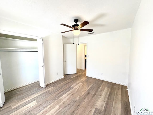unfurnished bedroom featuring visible vents, a ceiling fan, wood finished floors, a closet, and baseboards