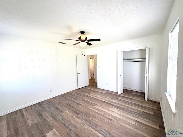 unfurnished bedroom featuring baseboards, ceiling fan, wood finished floors, a closet, and a textured ceiling
