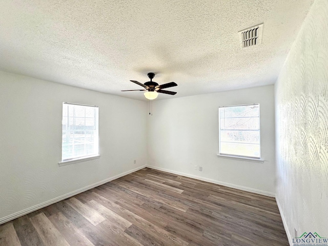 spare room with baseboards, wood finished floors, visible vents, and ceiling fan