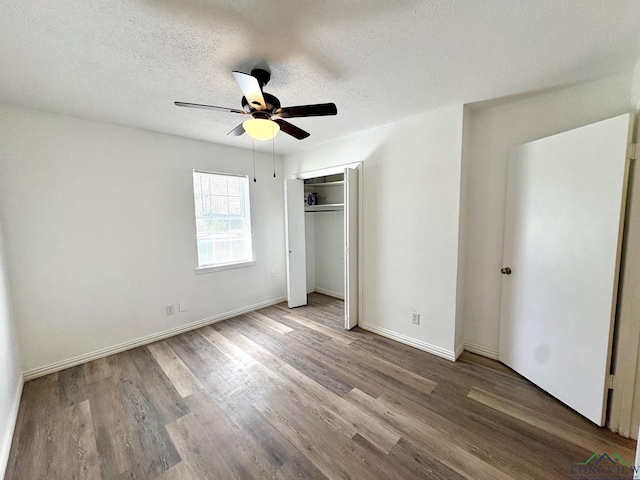 unfurnished bedroom with wood finished floors, baseboards, ceiling fan, a closet, and a textured ceiling