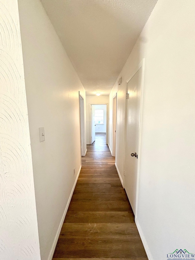 hallway with baseboards and dark wood-style floors