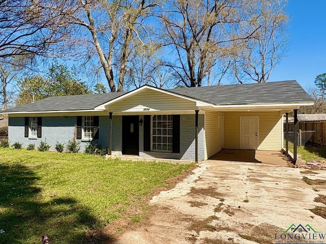 ranch-style home featuring brick siding, driveway, an attached carport, and a front lawn