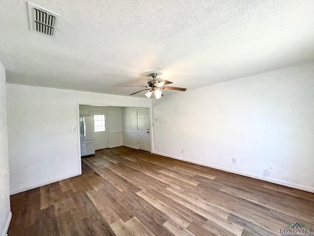 unfurnished room featuring visible vents, dark wood-type flooring, baseboards, ceiling fan, and a textured ceiling