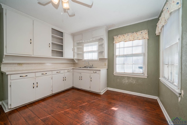 kitchen with dark hardwood / wood-style flooring, ornamental molding, ceiling fan, sink, and white cabinets