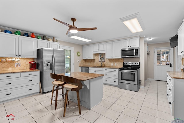 589 County Road 183, Carthage, TX 75633 - kitchen with appliances with stainless steel finishes, a sink, light tile patterned floors, tasteful backsplash, and ornamental molding