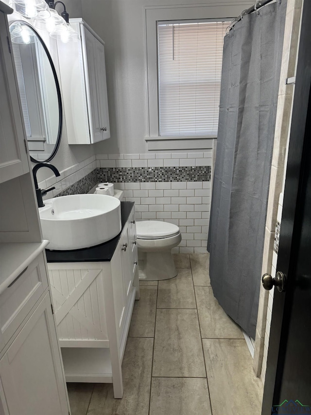 bathroom featuring vanity, tile patterned flooring, a shower with shower curtain, toilet, and tile walls