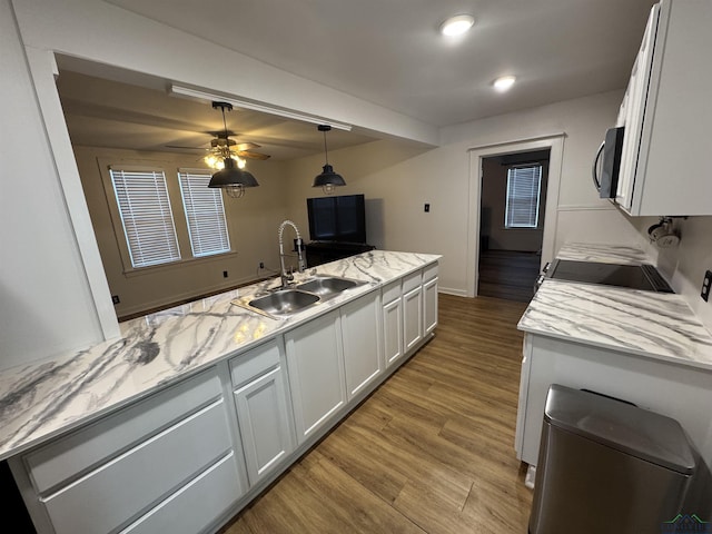 kitchen featuring light stone counters, sink, range, light hardwood / wood-style floors, and white cabinetry