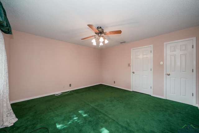 spare room with ceiling fan, dark carpet, and a textured ceiling