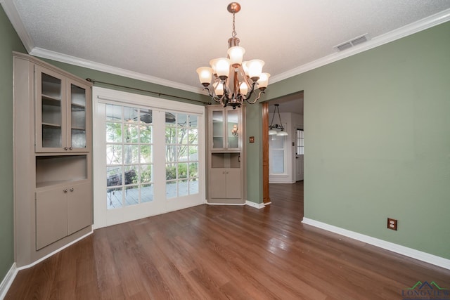 unfurnished dining area with dark hardwood / wood-style floors, crown molding, a textured ceiling, and an inviting chandelier