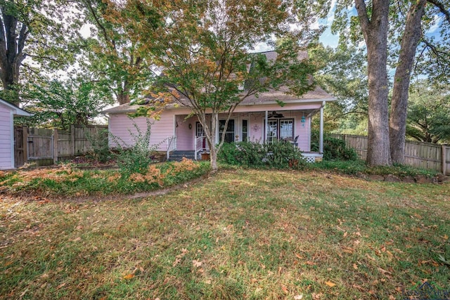 view of property hidden behind natural elements with a front lawn and covered porch