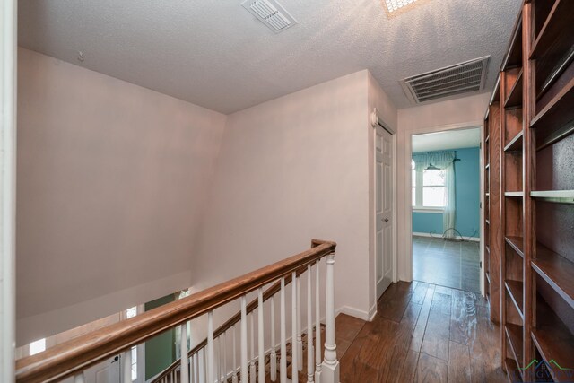 hallway with dark hardwood / wood-style flooring and a textured ceiling