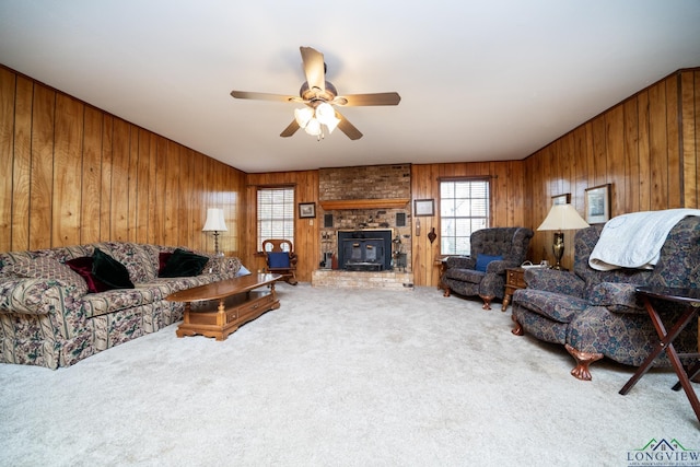 carpeted living room with ceiling fan, a fireplace, and wood walls