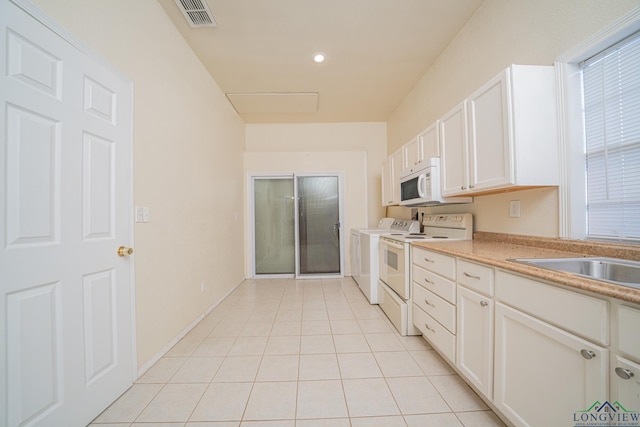 316 County Road 2750, Hughes Springs, TX 75656 - kitchen featuring white appliances, washer and dryer, white cabinetry, light countertops, and light tile patterned flooring