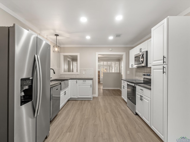 kitchen with backsplash, stainless steel appliances, pendant lighting, light hardwood / wood-style flooring, and white cabinetry