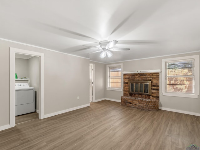 unfurnished living room with ceiling fan, washer / dryer, hardwood / wood-style flooring, a fireplace, and ornamental molding