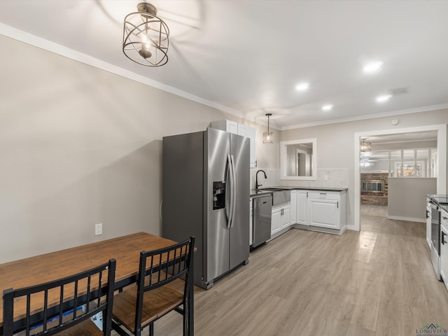 kitchen featuring decorative backsplash, appliances with stainless steel finishes, pendant lighting, light hardwood / wood-style floors, and white cabinetry