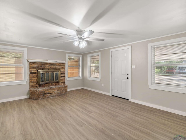 unfurnished living room featuring ceiling fan, ornamental molding, light hardwood / wood-style flooring, and a brick fireplace