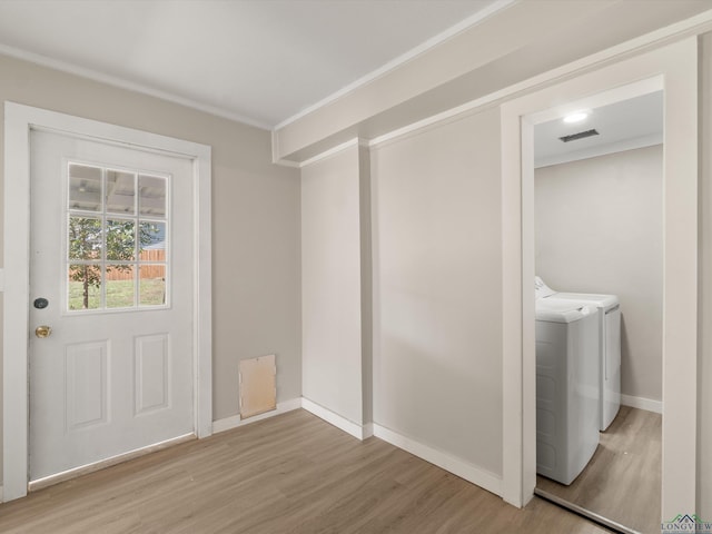 clothes washing area with light wood-type flooring, separate washer and dryer, and crown molding