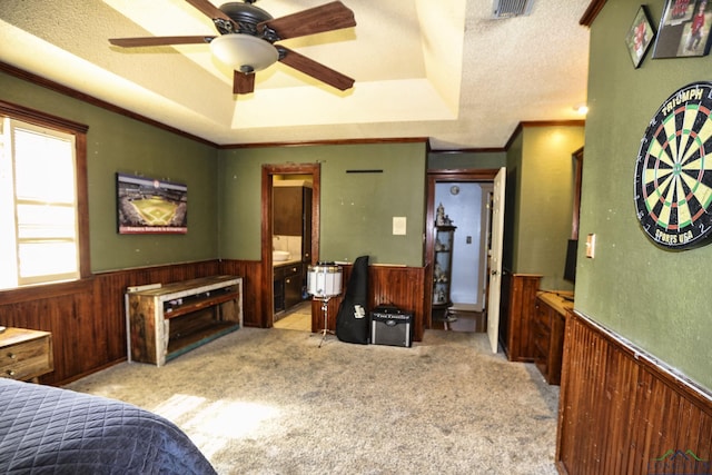 bedroom featuring ensuite bath, a textured ceiling, a tray ceiling, light colored carpet, and ceiling fan