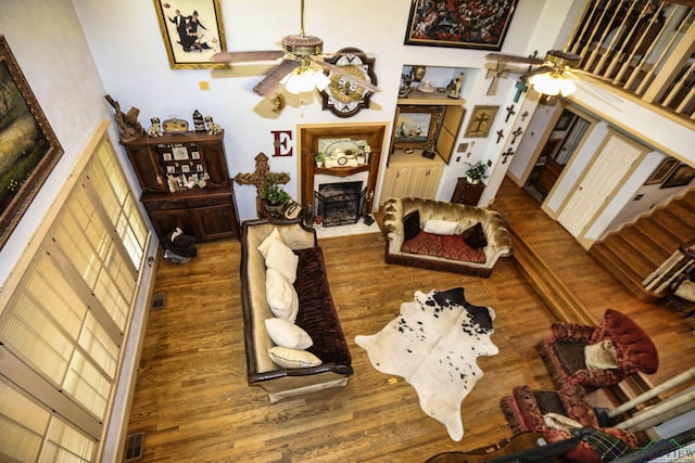 living room with a towering ceiling, hardwood / wood-style flooring, and ceiling fan