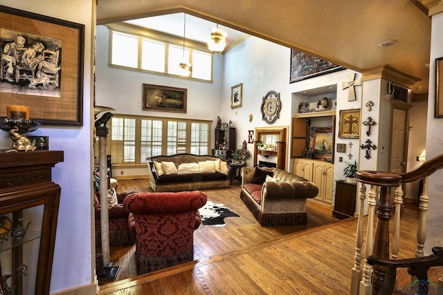 living room featuring light wood-type flooring, built in features, and a towering ceiling