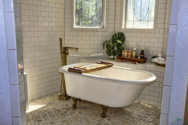 bathroom with tile patterned floors, a bathtub, and a healthy amount of sunlight