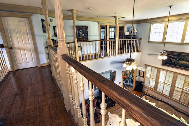 hall with ornate columns, crown molding, dark wood-type flooring, and a textured ceiling