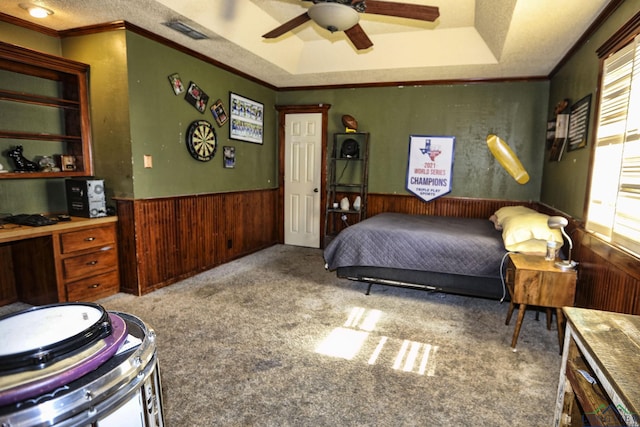 carpeted bedroom featuring a raised ceiling, multiple windows, ceiling fan, and crown molding