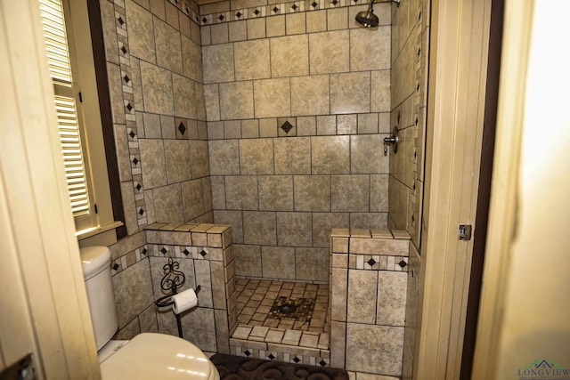 bathroom with tiled shower and toilet