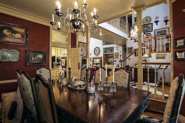 dining room with ornate columns, a chandelier, a high ceiling, and ornamental molding