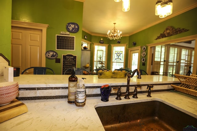 kitchen with pendant lighting, ornamental molding, sink, and a chandelier