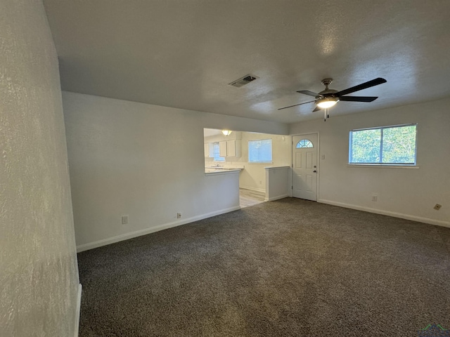 unfurnished room with dark colored carpet, ceiling fan, and a textured ceiling