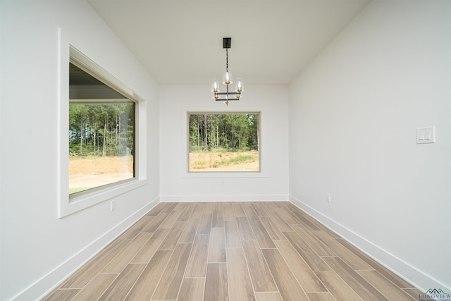 unfurnished dining area featuring light hardwood / wood-style flooring and a chandelier