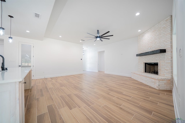 unfurnished living room with ceiling fan and a fireplace