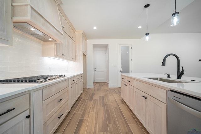 kitchen with sink, stainless steel appliances, pendant lighting, custom exhaust hood, and light wood-type flooring