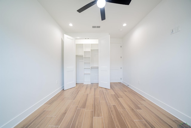 unfurnished bedroom featuring a closet, ceiling fan, light hardwood / wood-style flooring, and a walk in closet