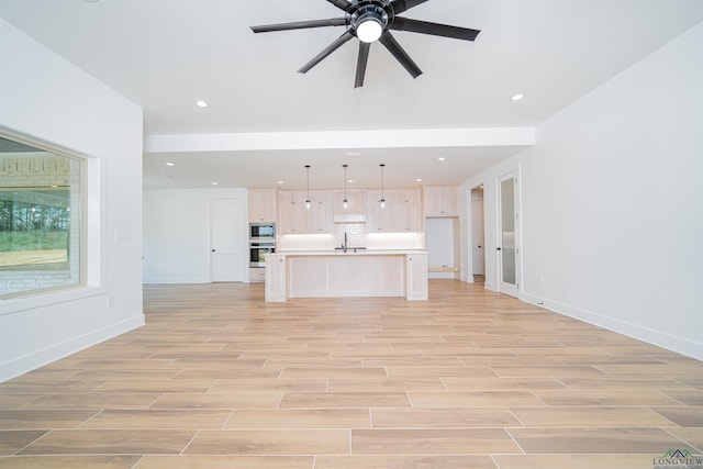 unfurnished living room featuring ceiling fan and sink