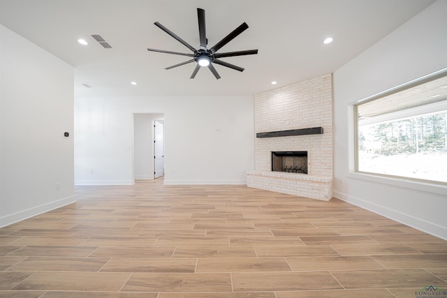 unfurnished living room with ceiling fan and a brick fireplace