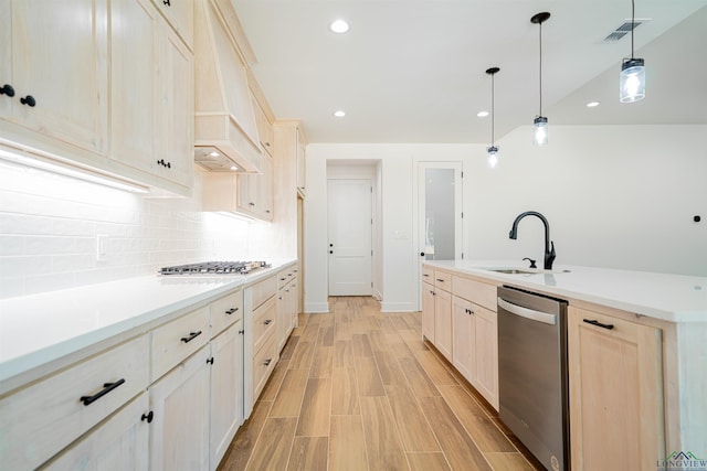 kitchen with pendant lighting, premium range hood, sink, light hardwood / wood-style flooring, and stainless steel appliances